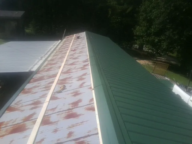 Old rusted panels beside newly installed green metal roofing — Wind Damage Roof Repair by Roofing Brothers in Bohemia