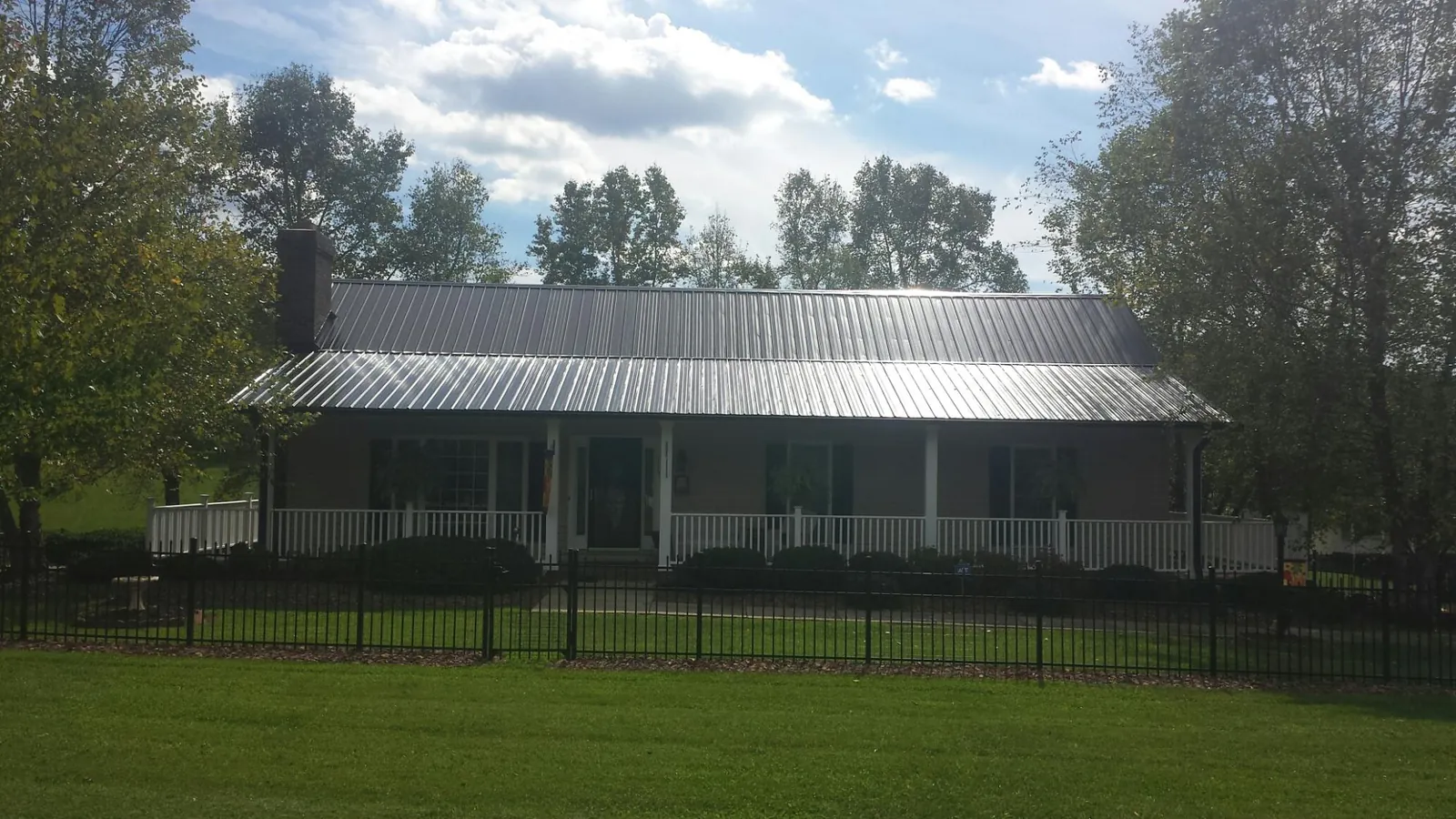 Gray metal roof on a brick ranch with a full width front porch — Gutter Guard Installation work by our crew in Bohemia