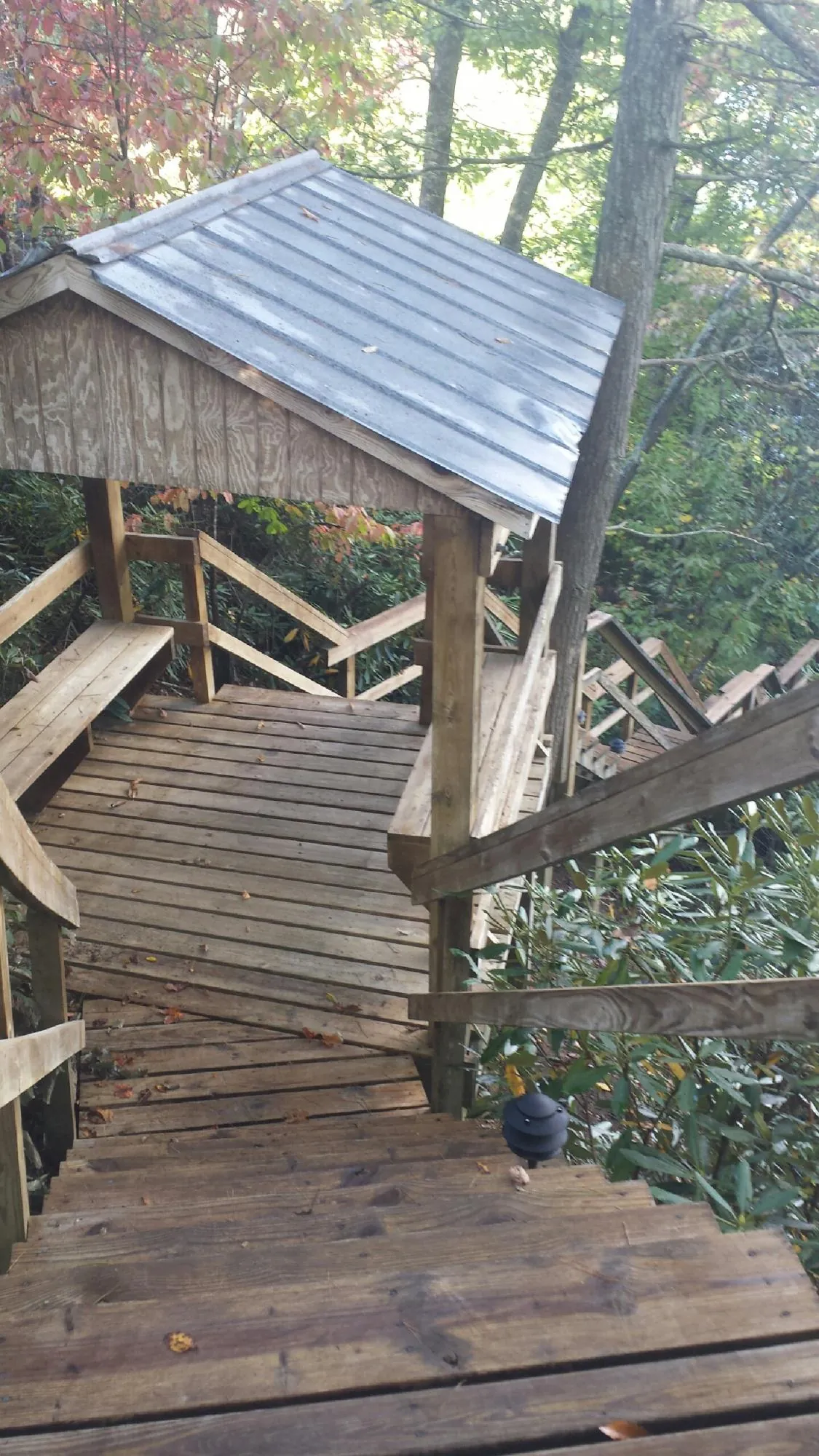 Metal roofed shelter over wooden steps on a wooded walkway — Skylight Repair & Installation work by our crew in Bohemia