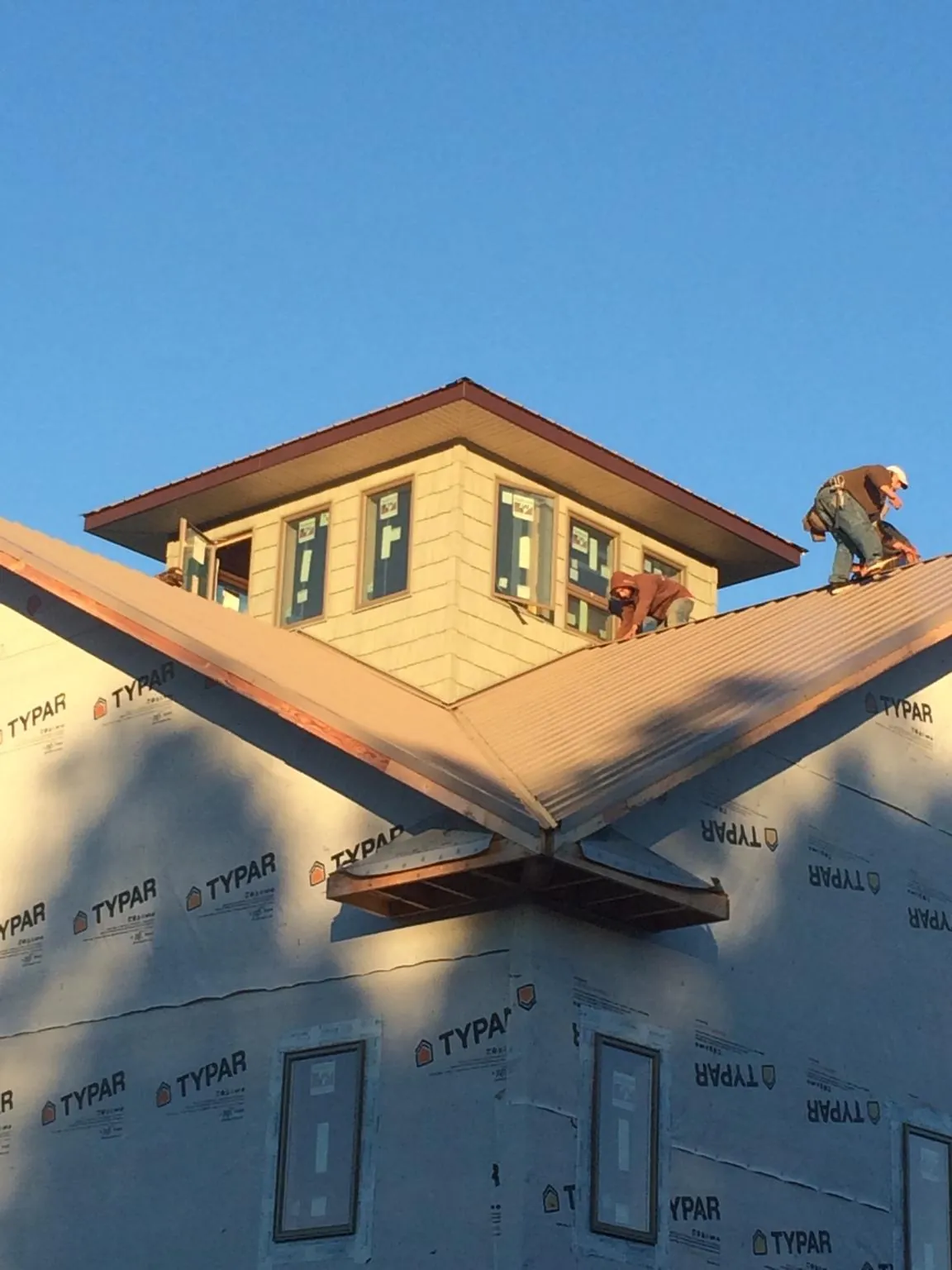 Roofers working around a rooftop cupola on a new metal roof at sunset — Roof Waterproofing in Bohemia by Roofing Brothers